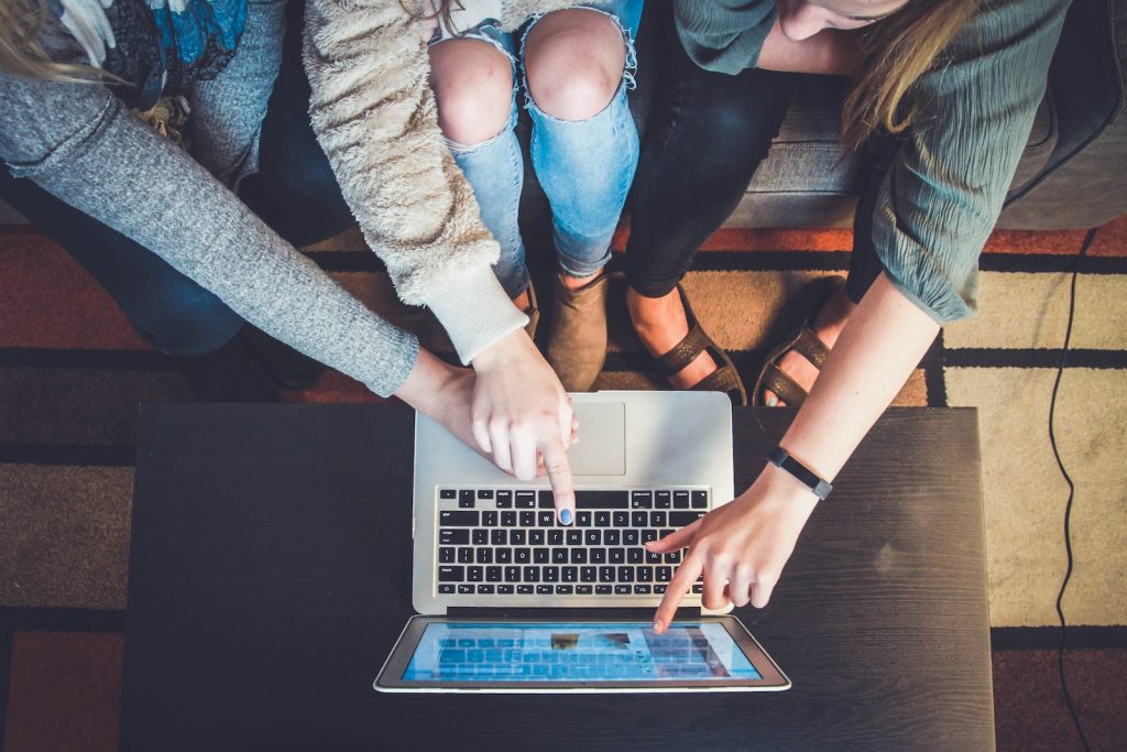 three person pointing the silver laptop computer - grow your business by promoting it